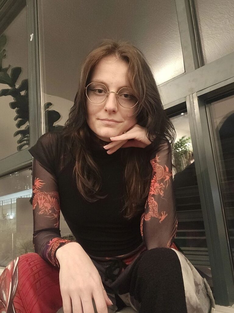 Ayla Derrick, seated indoors, resting her chin on her hand.